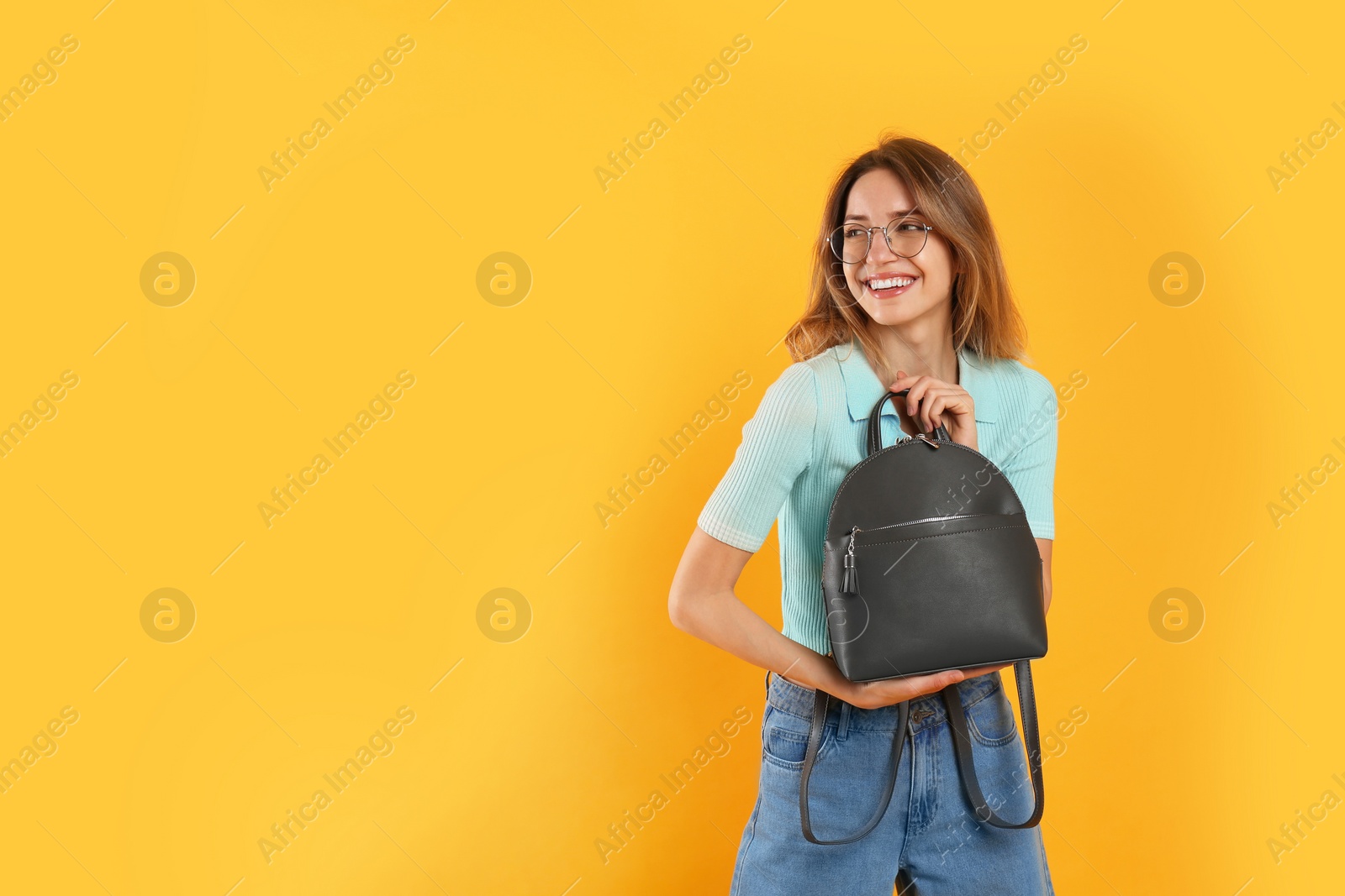 Photo of Happy woman with backpack on yellow background. Space for text