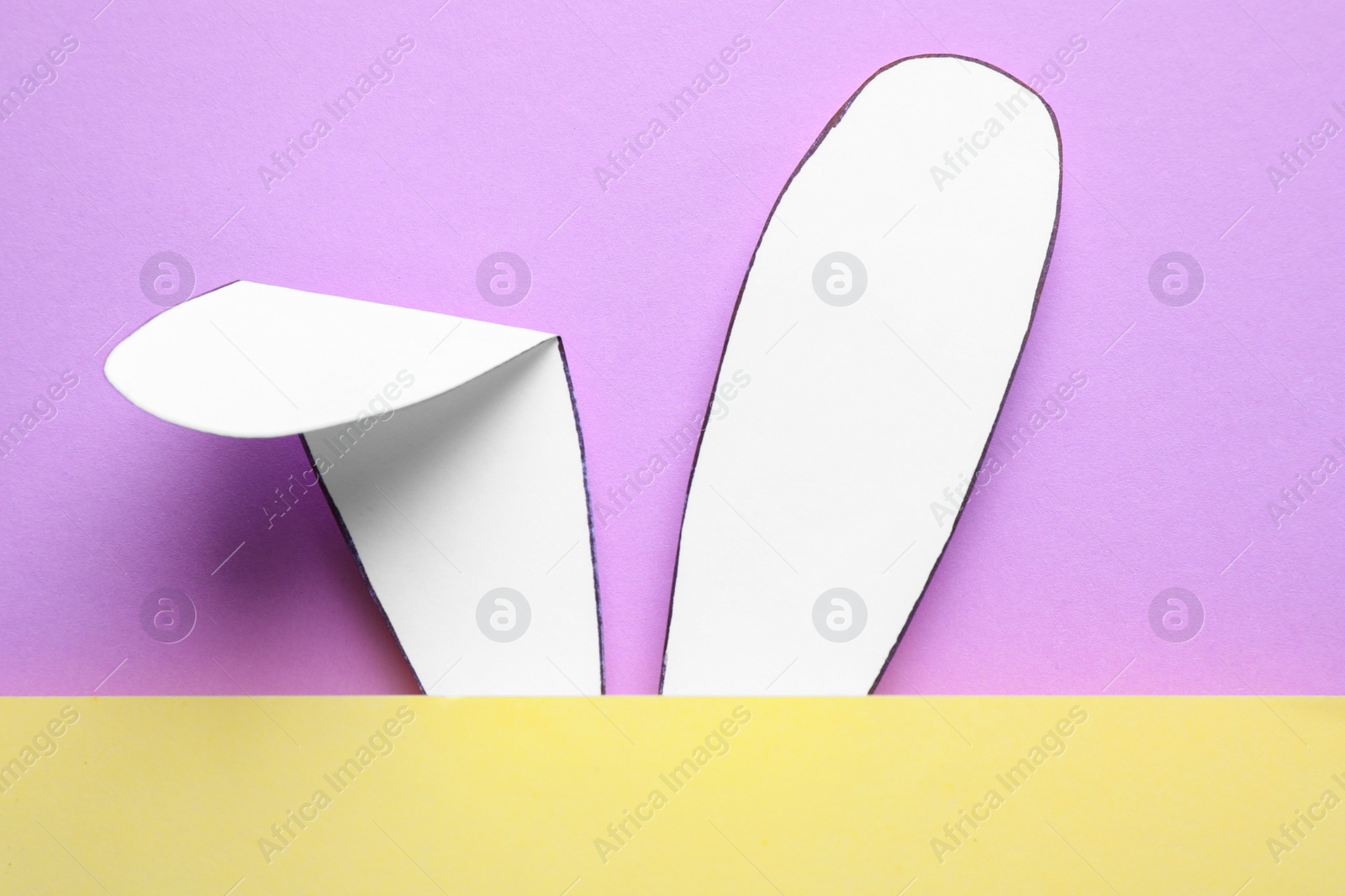 Photo of Top view of paper bunny ears on pale violet background. Easter celebration