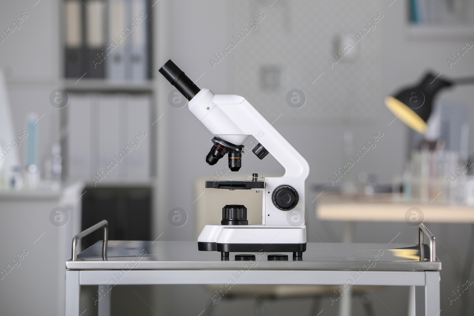 Photo of Modern medical microscope on metal table in laboratory