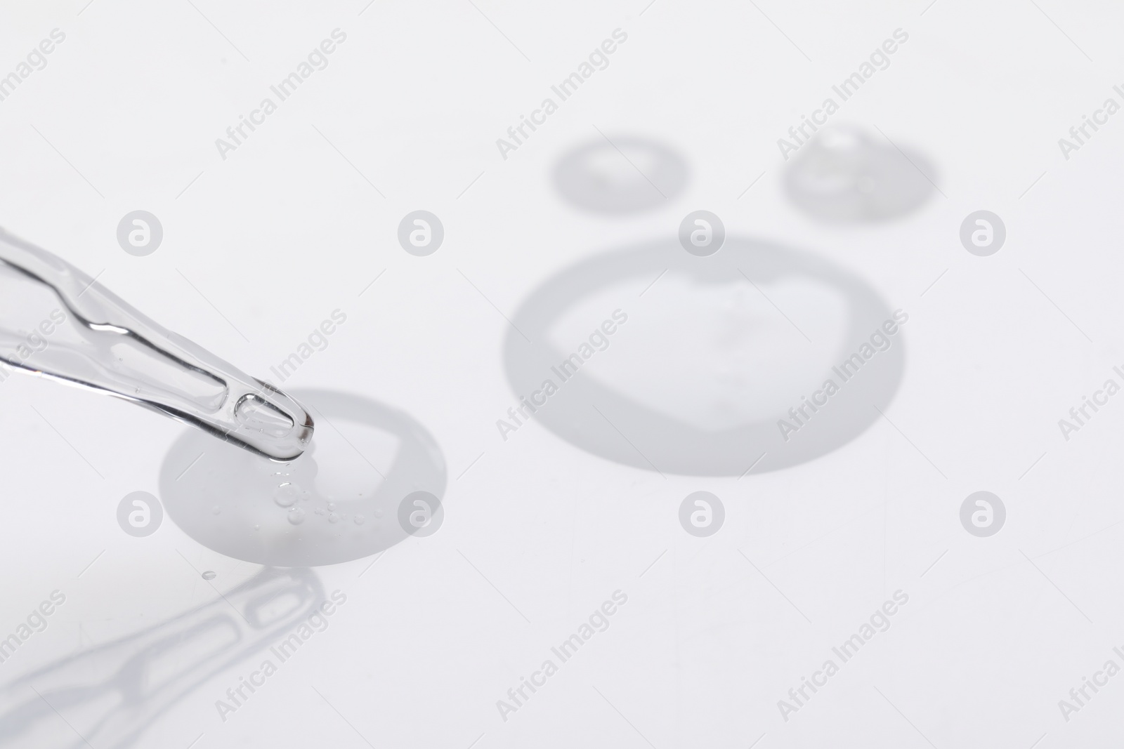 Photo of Glass pipette and transparent liquid on white background, closeup