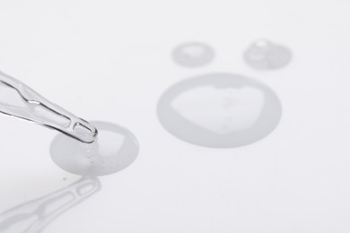 Glass pipette and transparent liquid on white background, closeup