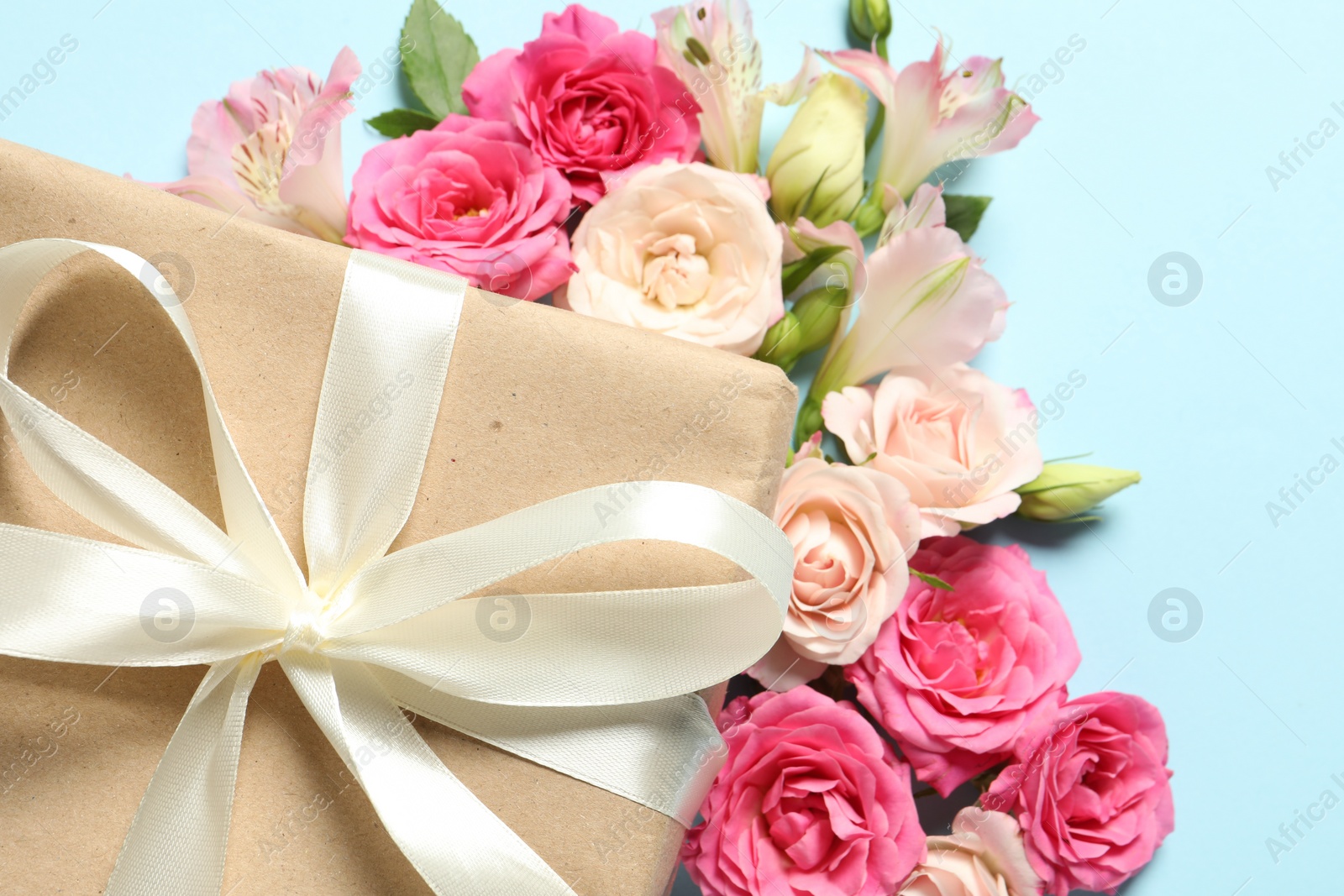 Photo of Happy Mother's Day. Beautiful flowers and gift box on light blue background, flat lay