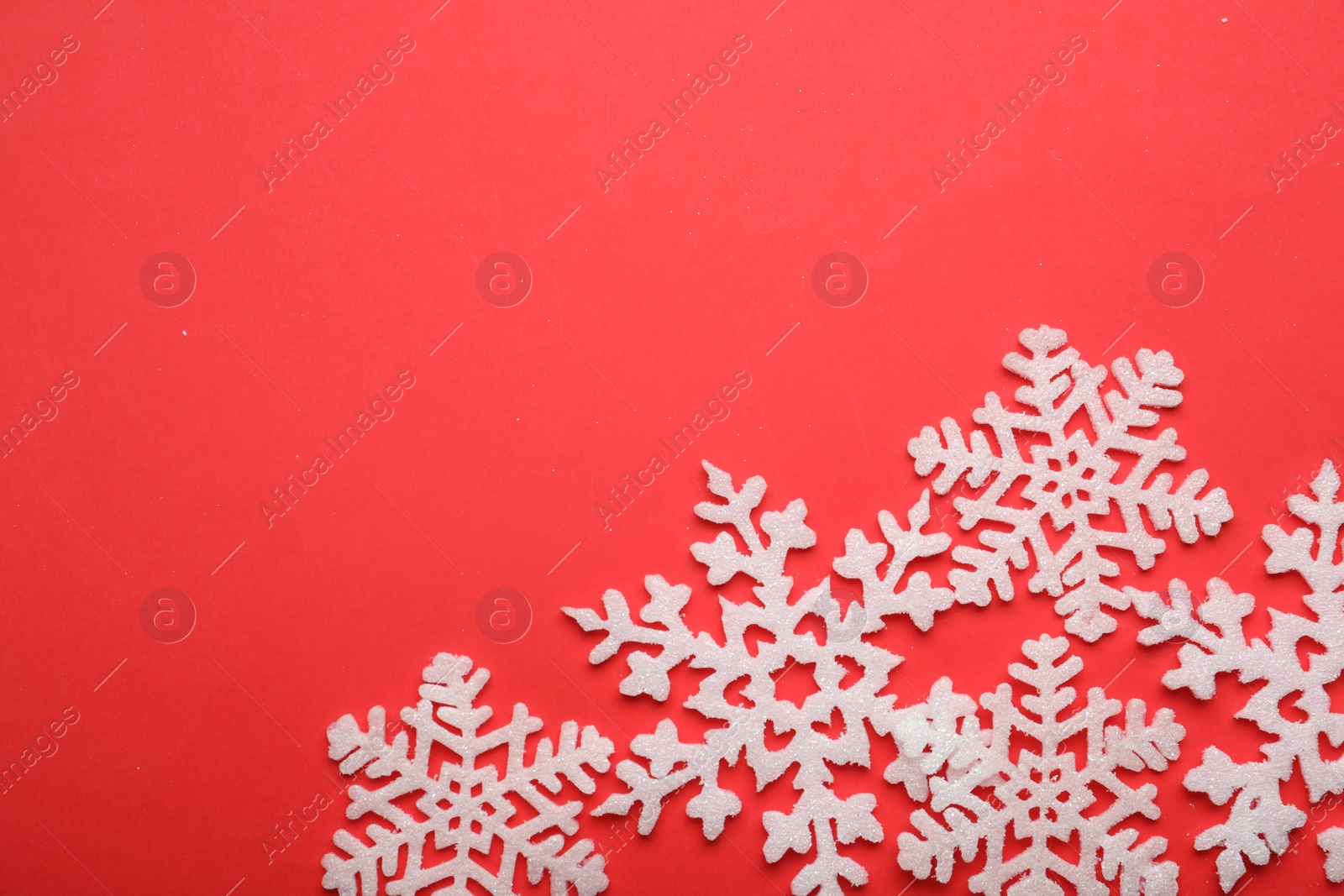 Photo of Beautiful decorative snowflakes on red background, flat lay. Space for text