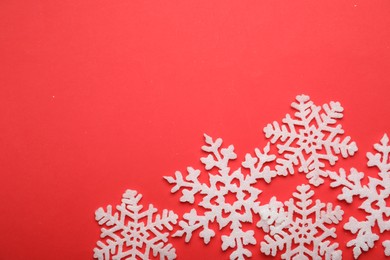 Beautiful decorative snowflakes on red background, flat lay. Space for text