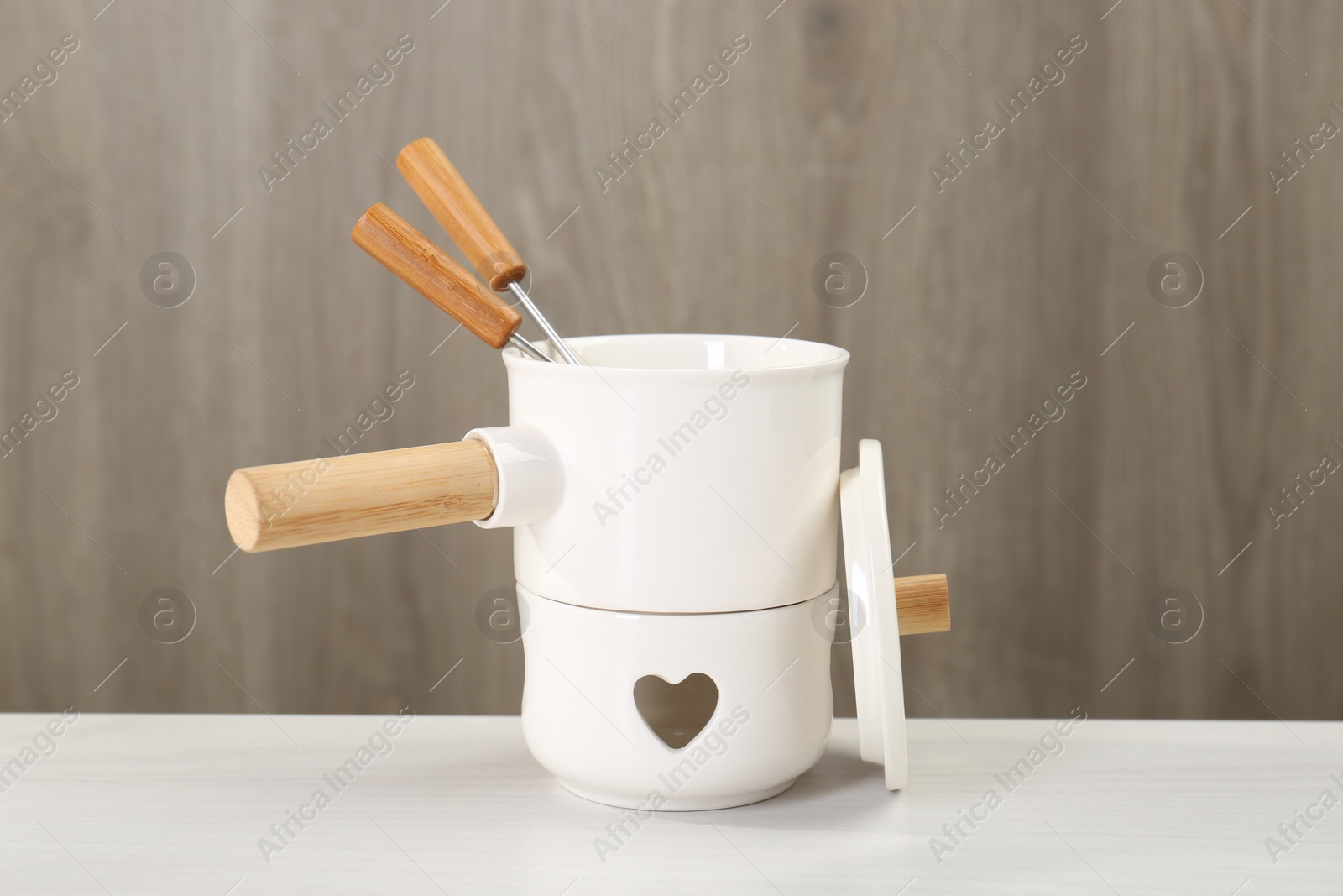 Photo of Fondue set on white wooden table. Kitchen equipment