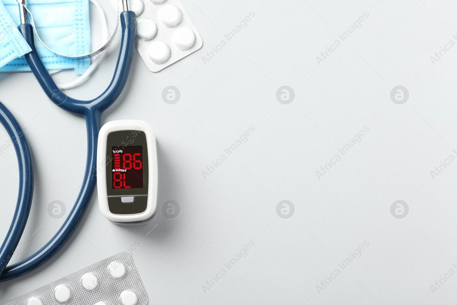 Photo of Flat lay composition with modern fingertip pulse oximeter and medical items on white background. Space for text