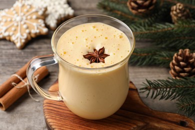 Photo of Glass of delicious eggnog with anise star on wooden table