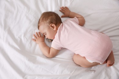 Photo of Adorable little baby with pacifier sleeping on bed, top view