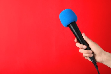 Photo of Woman holding modern microphone on color background, closeup. Space for text