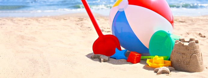 Image of Different sand toys and beach ball near sea, space for text. Banner design