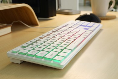 Modern RGB keyboard on wooden table indoors, closeup