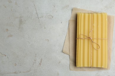 Uncooked lasagna sheets tied with rope on light grey table, top view. Space for text