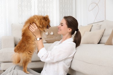 Happy young woman with cute dog in living room