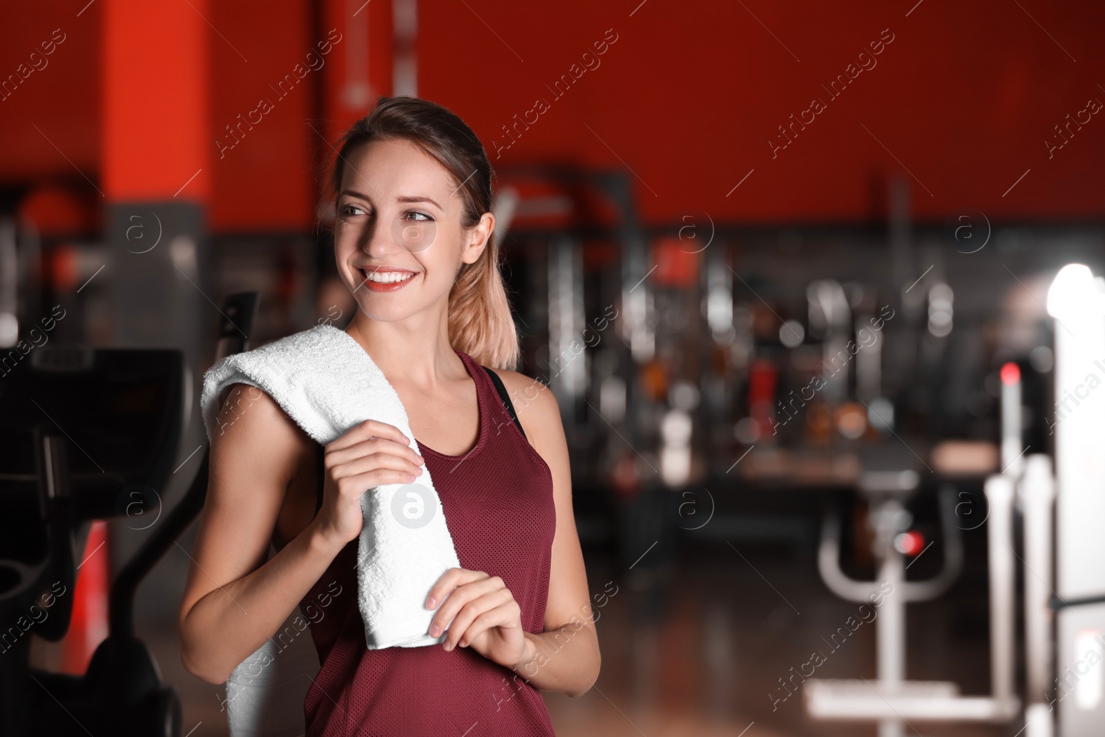 Photo of Beautiful young woman with towel in gym. Space for text