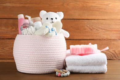 Photo of Basket with different baby cosmetic products, accessories and toys on wooden table