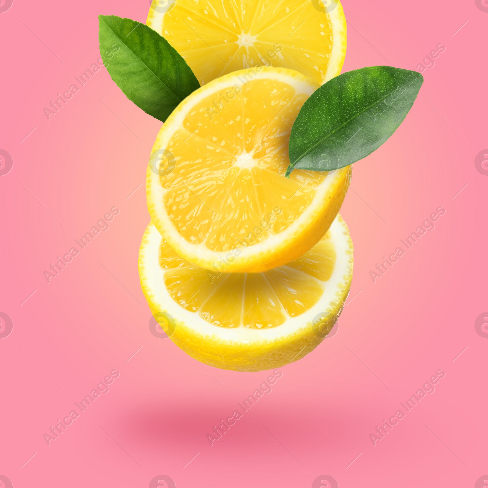 Image of Cut fresh lemons with green leaves falling on hot pink background