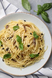 Photo of Delicious pasta with anchovies, olives and basil on light grey table, flat lay