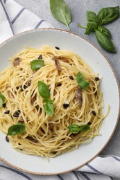 Delicious pasta with anchovies, olives and basil on light grey table, flat lay