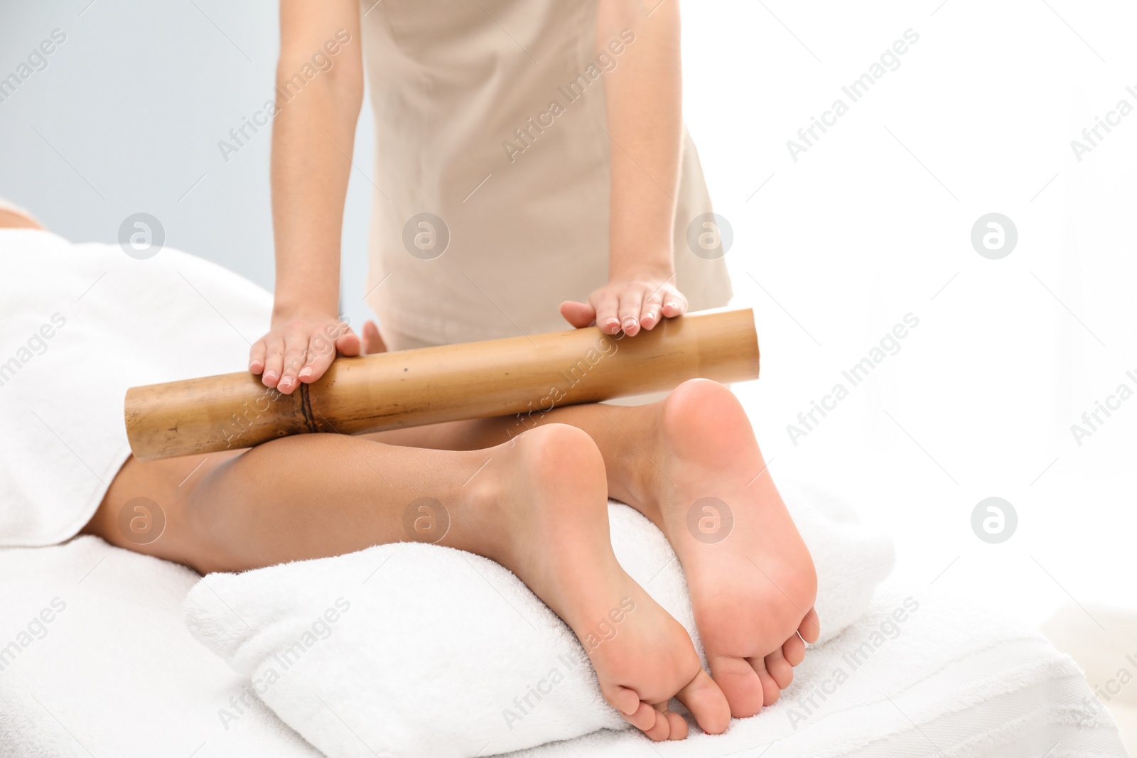 Photo of Woman having massage with bamboo stick in wellness center