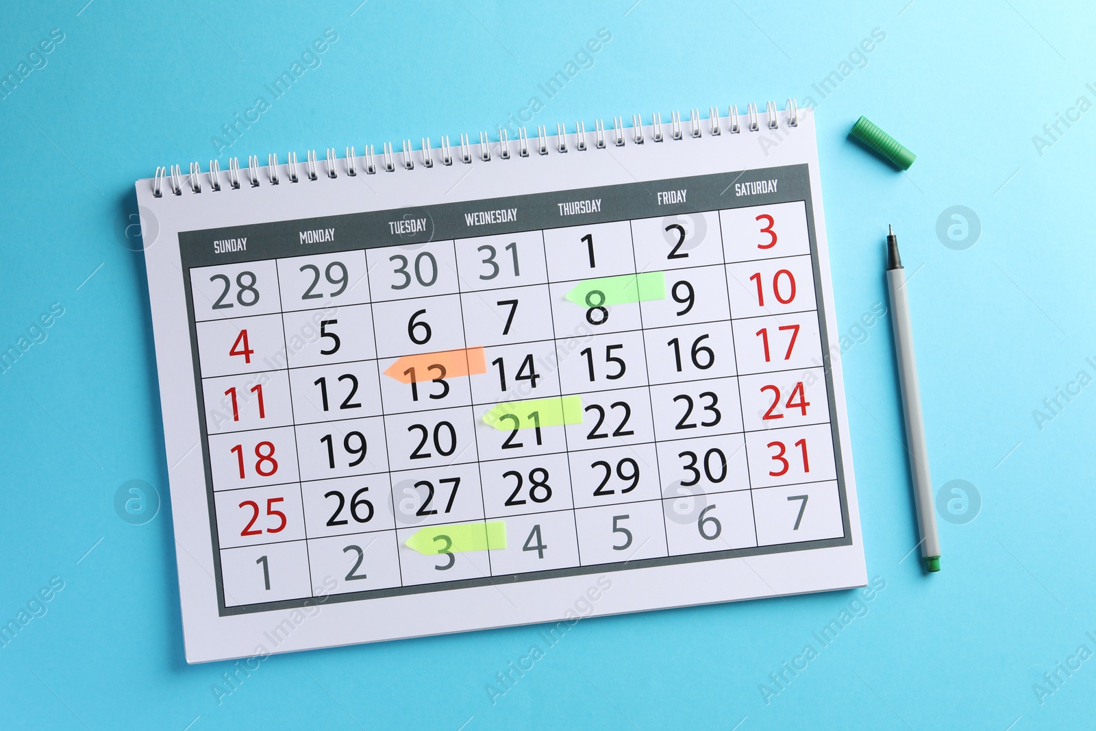 Photo of Timetable. Calendar with marked dates and pen on light blue background, top view