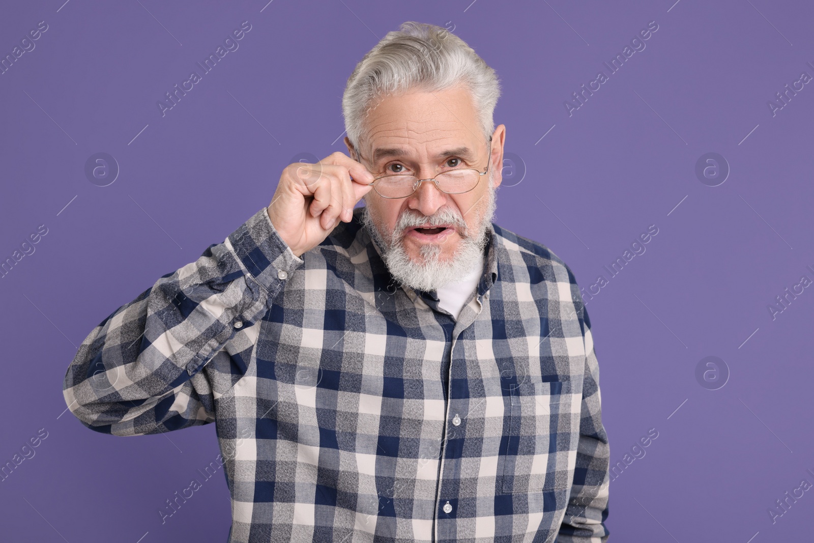 Photo of Portrait of surprised senior man on violet background