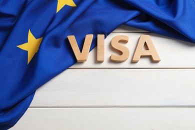 Word Visa made of letters and European Union flag on white wooden table, flat lay. Space for text
