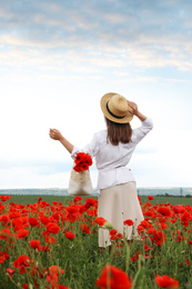 Woman with handbag and poppy flowers in beautiful field
