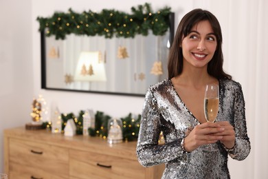 Photo of Smiling woman with glass of champagne celebrating Christmas at home. Space for text