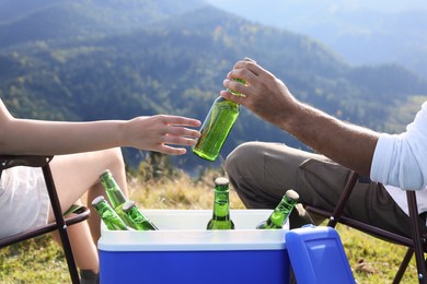 Photo of Couple and cool box with bottles of beer in nature, closeup