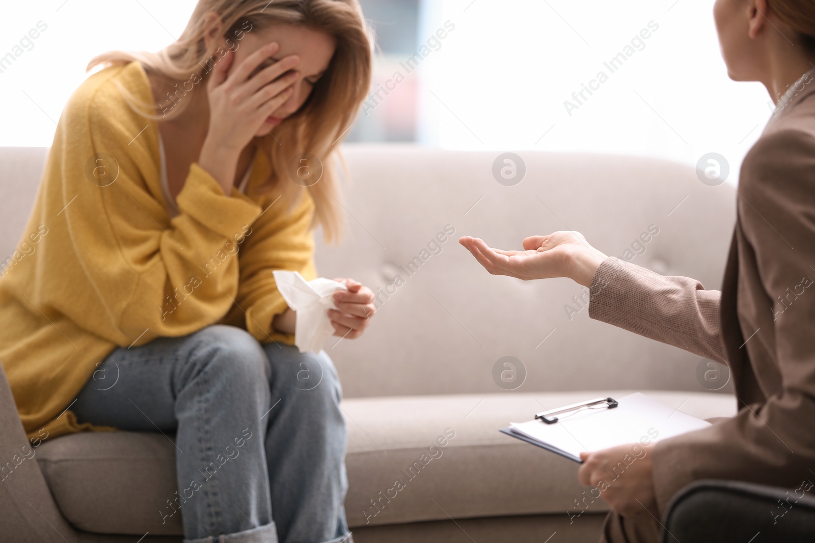 Photo of Psychotherapist working with young woman in light office