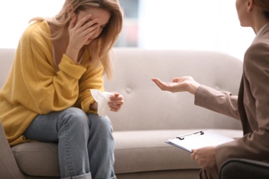 Psychotherapist working with young woman in light office