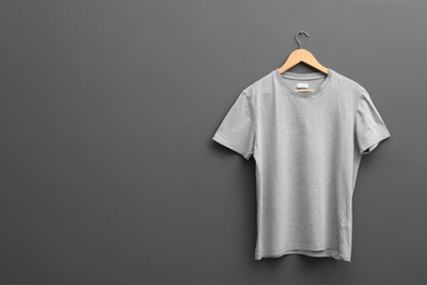 Photo of Hanger with blank t-shirt on grey background. Mockup for design