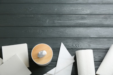 Clean napkins, box with tissues and rolls of paper towels on grey wooden table, flat lay. Space for text