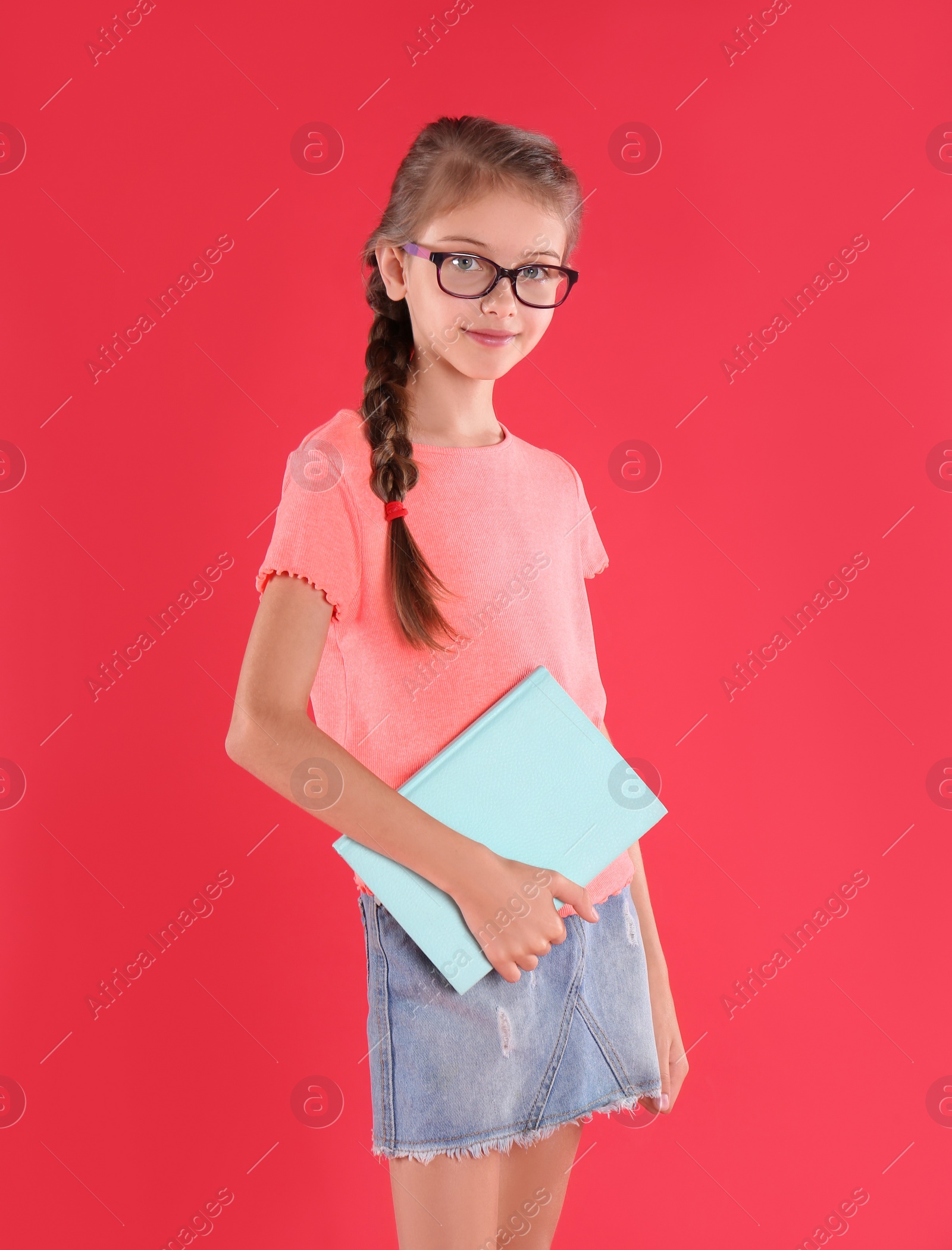 Photo of Cute little girl with book on red background