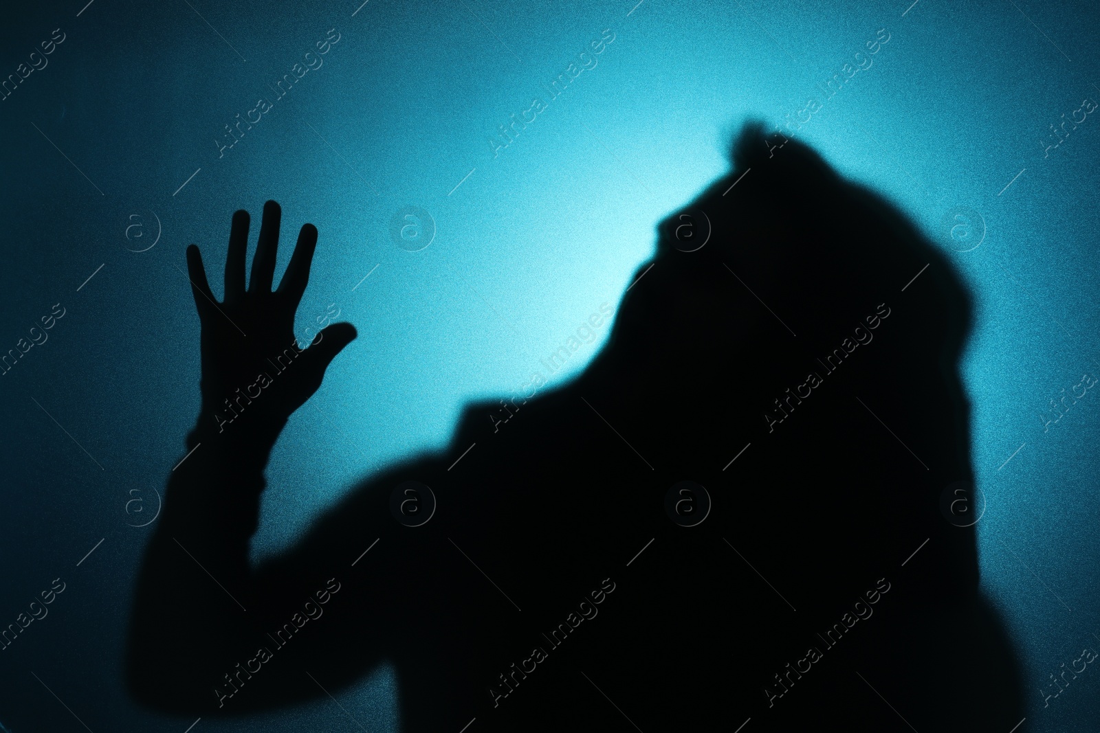 Photo of Silhouette of ghost behind glass against blue background