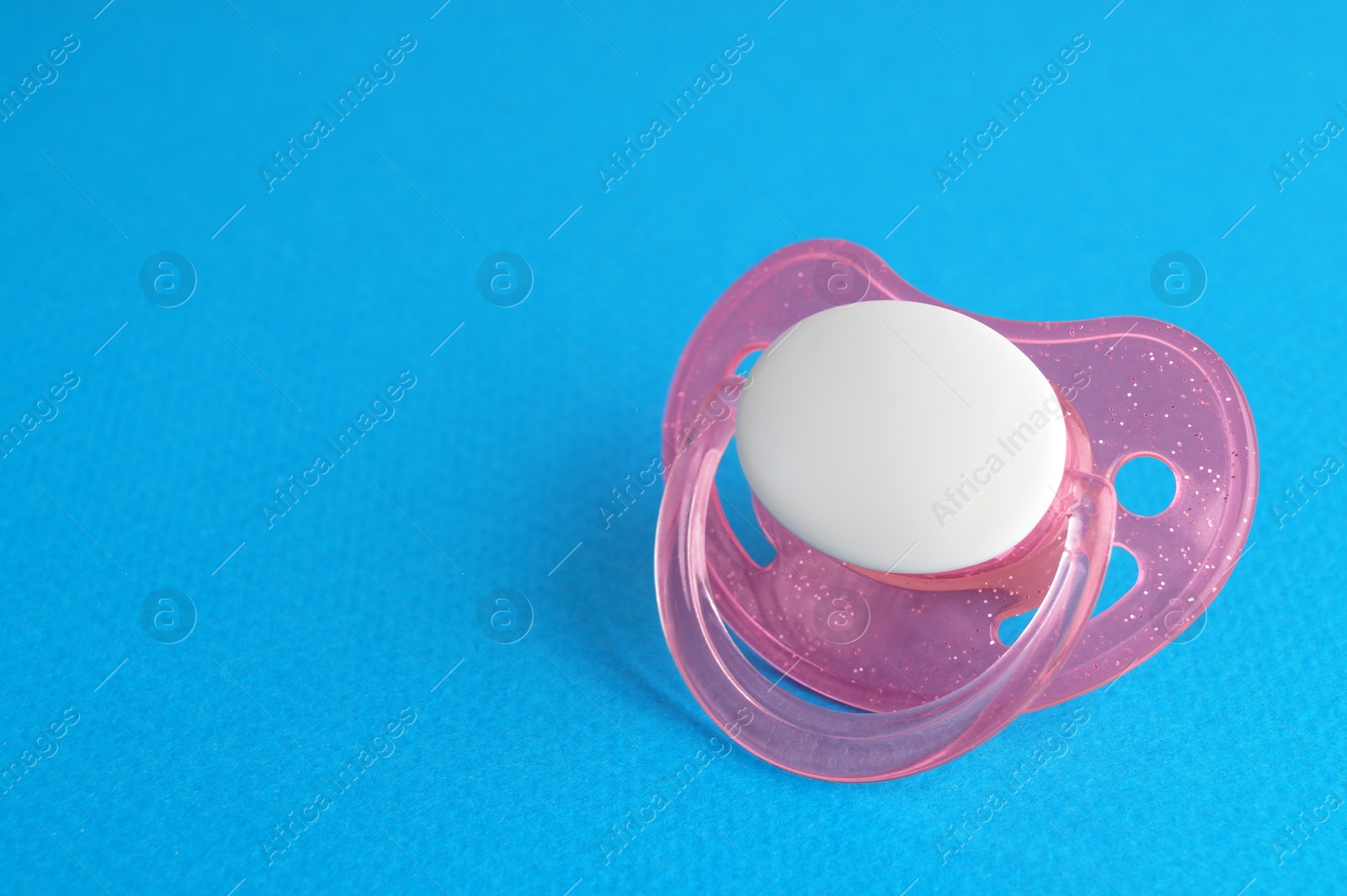 Photo of One new baby pacifier on blue background, space for text