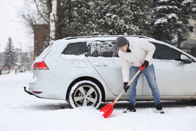 Photo of Man removing snow with shovel near car outdoors