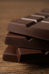 Photo of Pieces of tasty chocolate bars on wooden table, closeup