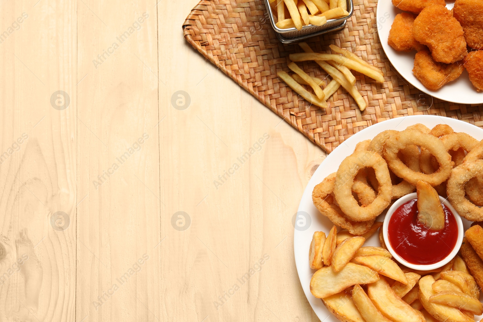 Photo of Different snacks and tasty ketchup on wooden table, flat lay. Space for text