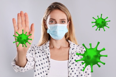 Image of Stop Covid-19 outbreak. Woman wearing medical mask surrounded by virus on light background