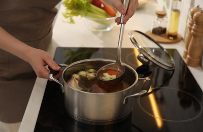 Photo of Woman making delicious bouillon in kitchen, closeup. Homemade recipe