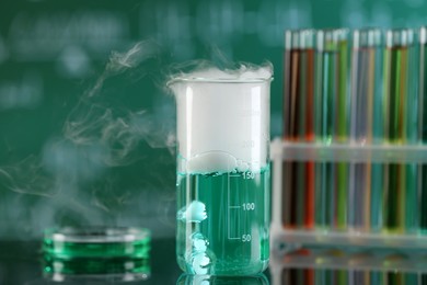 Photo of Laboratory glassware and test tubes with colorful liquids on glass table. Chemical reaction