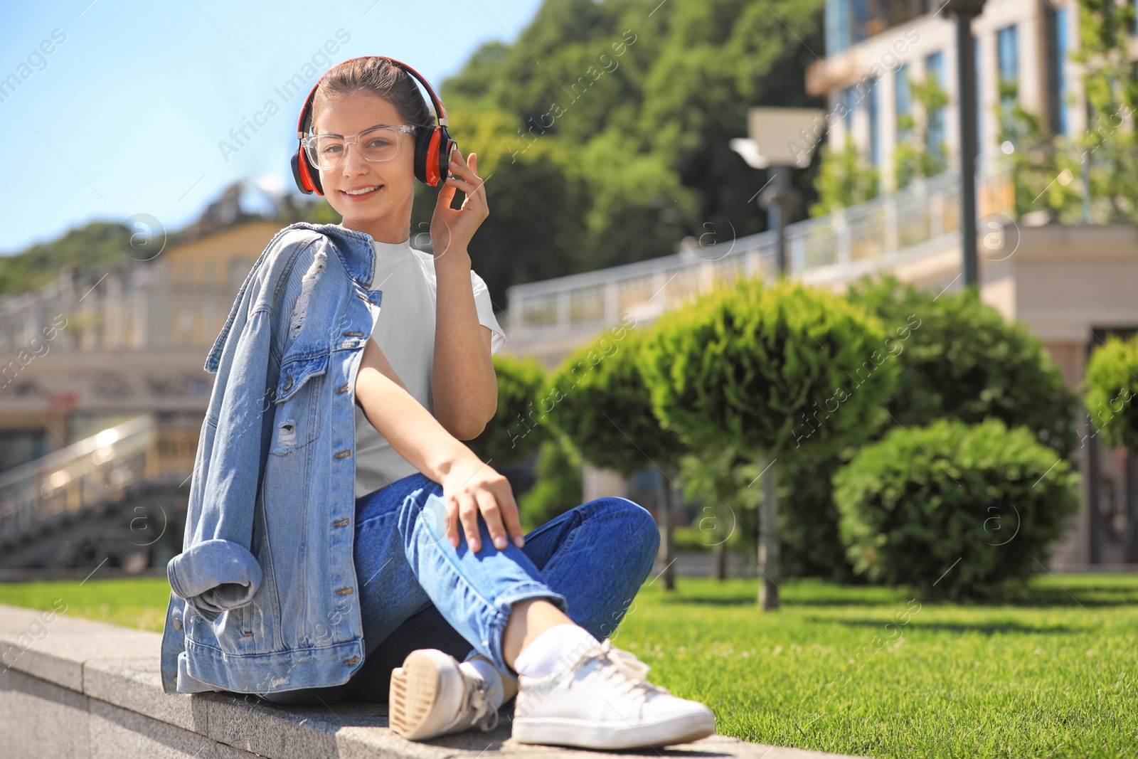 Photo of Young woman with headphones listening to music on city street. Space for text