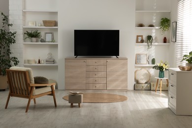 Photo of Stylish wide TV set on wooden cabinet in room