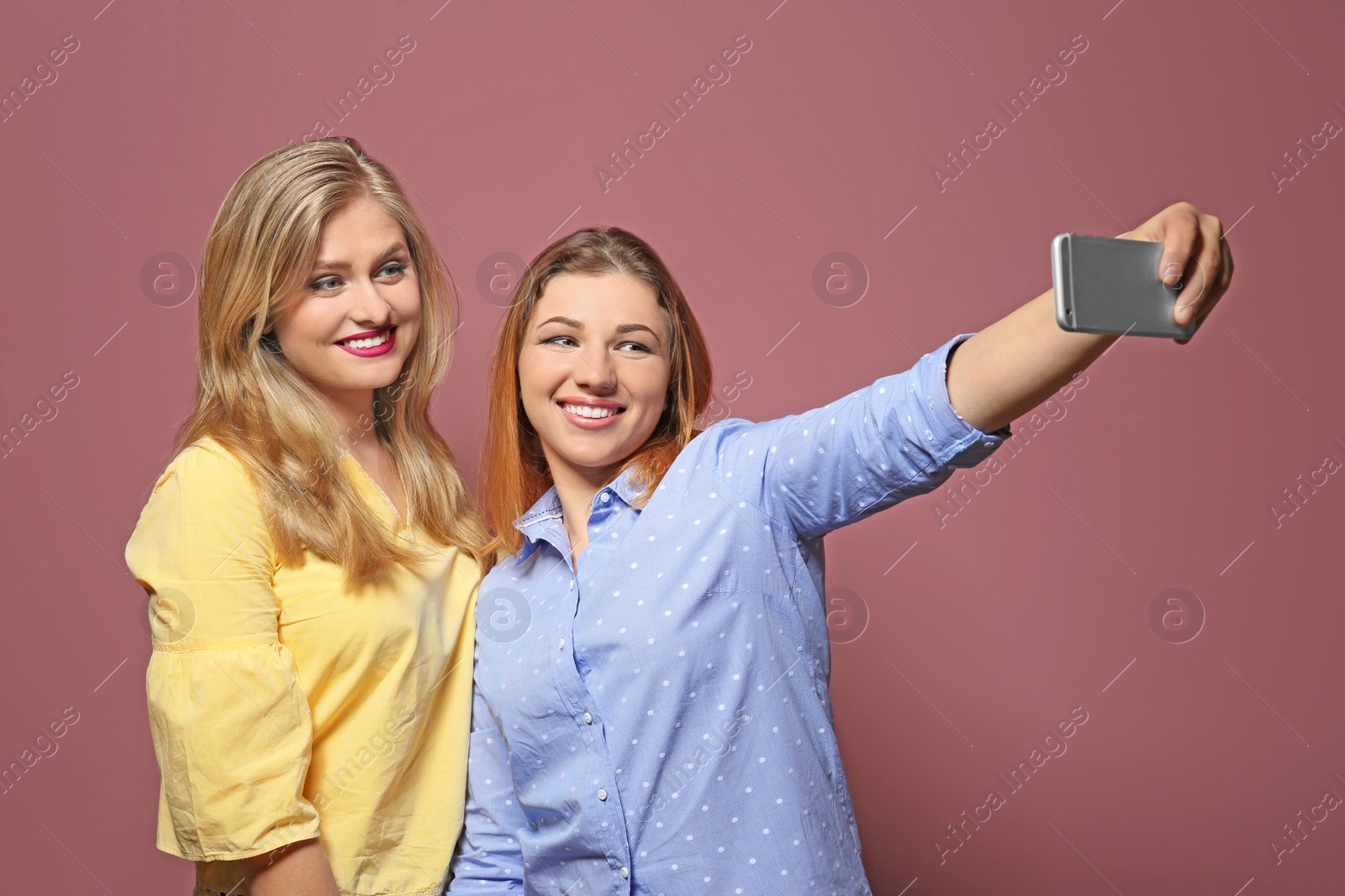 Photo of Attractive young women taking selfie on color background