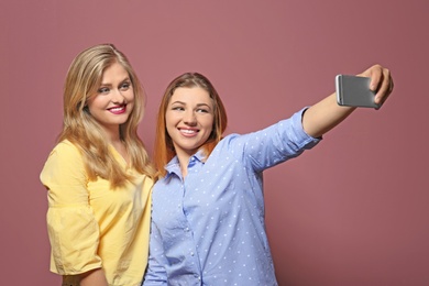 Attractive young women taking selfie on color background