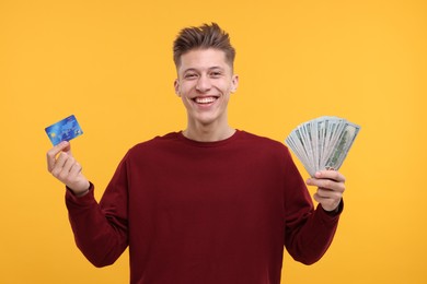 Photo of Happy man with dollar banknotes and credit card on yellow background