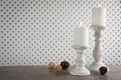 Photo of Elegant candlesticks with burning candles on marble table. Space for text