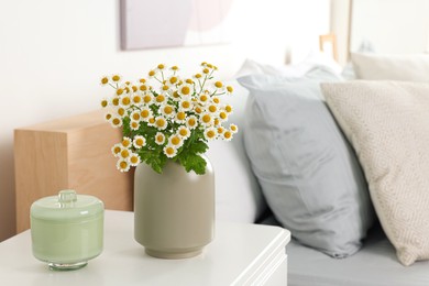 Photo of Beautiful bouquet of chamomile flowers on white nightstand in bedroom, space for text. Interior element