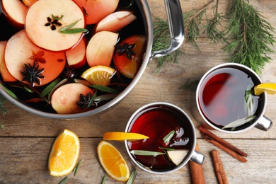 Tasty mulled wine with spices on wooden table, flat lay